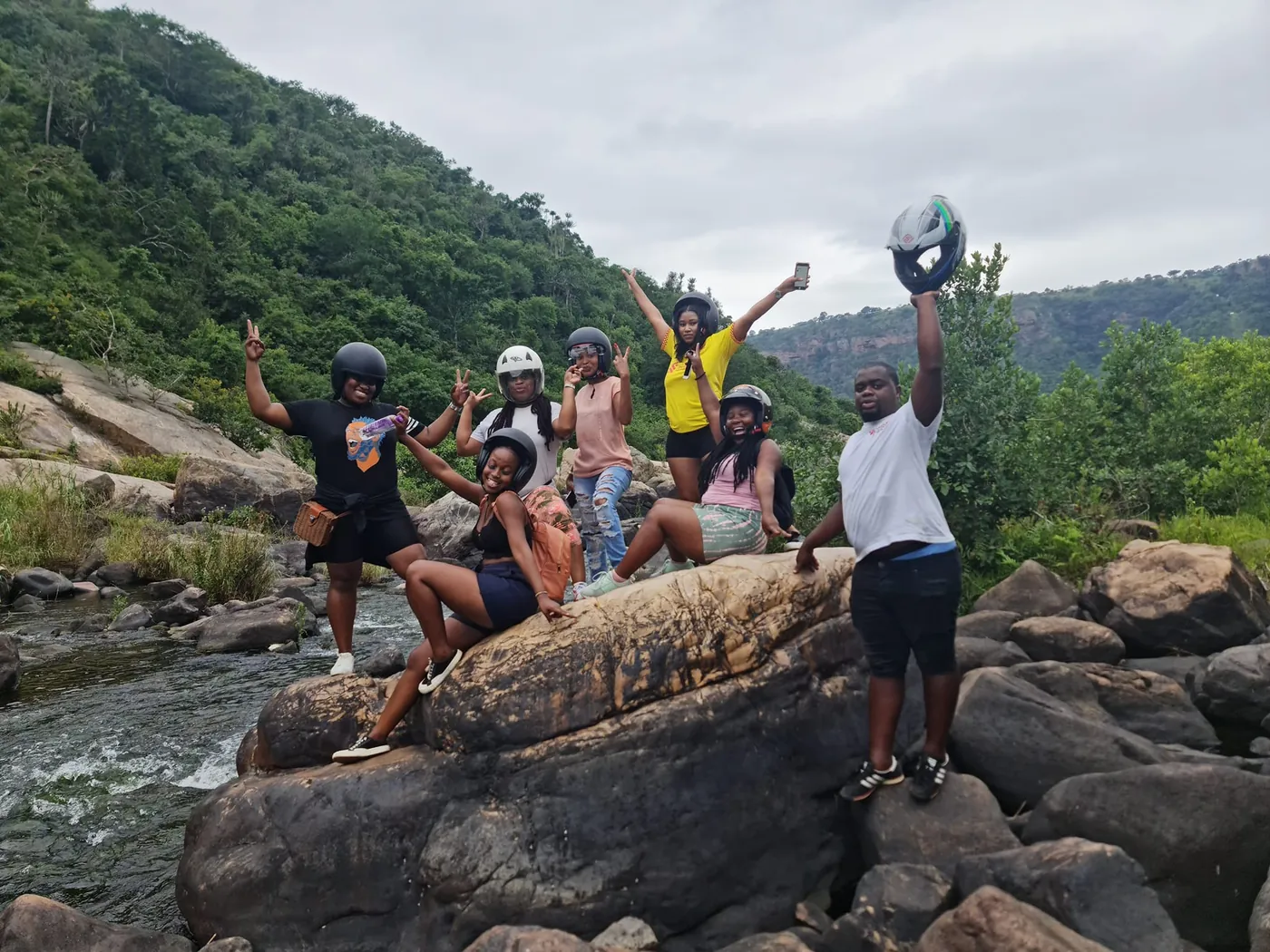 A family group cheering on the rocks by the river after their ride