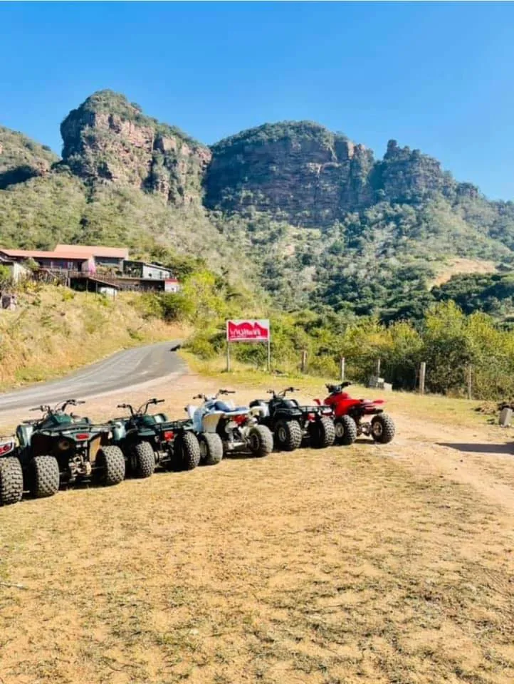 A row of quad bikes parked below sandstone cliffs under a blue sky